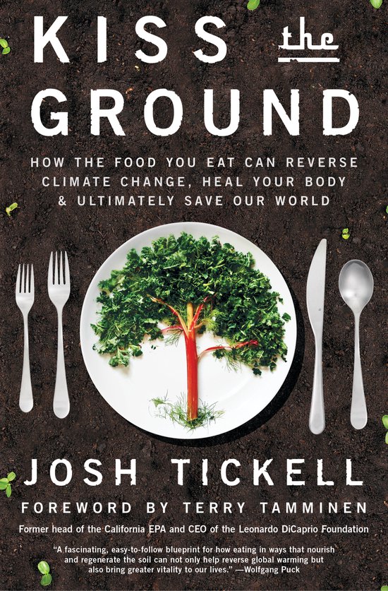 Boek "Kiss the Ground" met een bord waarop een boompje van boerenkool en rode biet is, omringd door bestek op aarde.