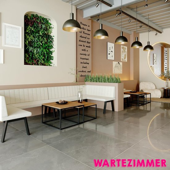 Stijlvolle wachtkamer met witte hoekbank, houten tafels, planten en kunst aan de muur.
