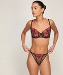 Model draagt zwarte beha en slip met rode bloemenbroderie.