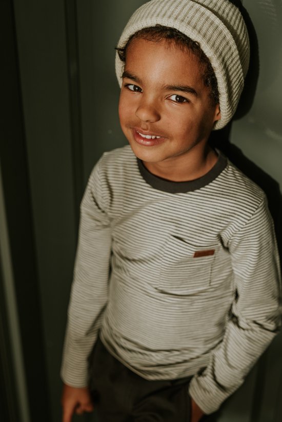 Close-up van een jongen met een lichtgrijs gestreept longsleeve T-shirt met een borstzak en een gebreide muts.