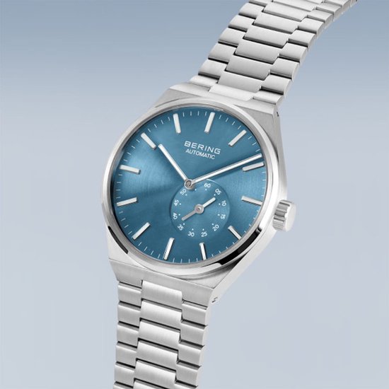 Zilverkleurig horloge met blauwe wijzerplaat met datumweergave en zilverkleurige band. BERING AUTOMATIC.