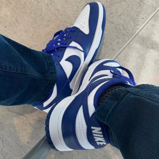 Nike Dunk Low 'Concord' sneakers met blauwe en witte panelen, gedragen met een jeans.