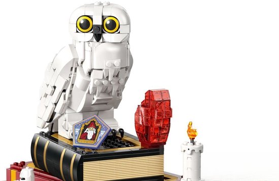 LEGO uil bovenop een stapel boeken met een rode edelsteen en een kaars.