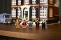 Vijf LEGO-figuren staan op een houten tafel. Op de achtergrond staat een LEGO-huis.