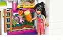 Een LEGO Friends poppetje met een roze outfit die een axolotl in een aquarium eten geeft.