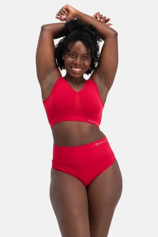 Een vrouw met een grote afro, draagt een rode naadloze bh zonder beugel. Ze heeft haar armen boven haar hoofd.