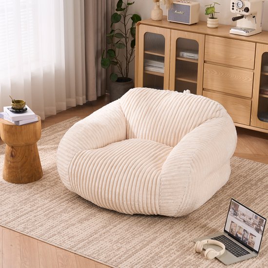 Donzige, beige corduroy zitzak in een woonkamer, naast een houten bijzettafel.