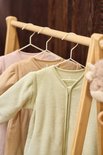 Drie baby slaapzakken in pastelkleuren: lichtroze, beige en mintgroen, hangend aan een houten rek.