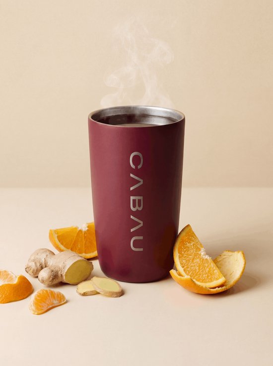 Bordeauxrode thermosbeker met "CABAU" logo, omringd door sinaasappelschijfjes en gember.