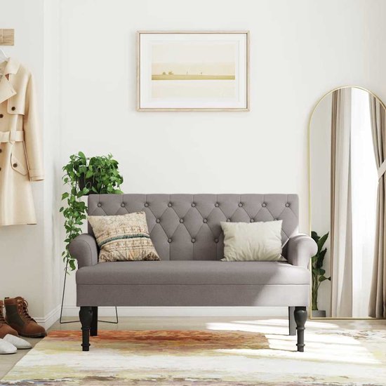 Grijze bank met knopen, gestyled in een hal met spiegel en kapstok.