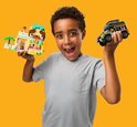 Garçon aux cheveux bouclés en t-shirt gris tenant une animalerie rose et une jeep, toutes deux en LEGO.