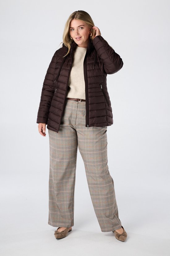 Model in bruine licht gewatteerde jas met capuchon, beige trui en geruite broek.