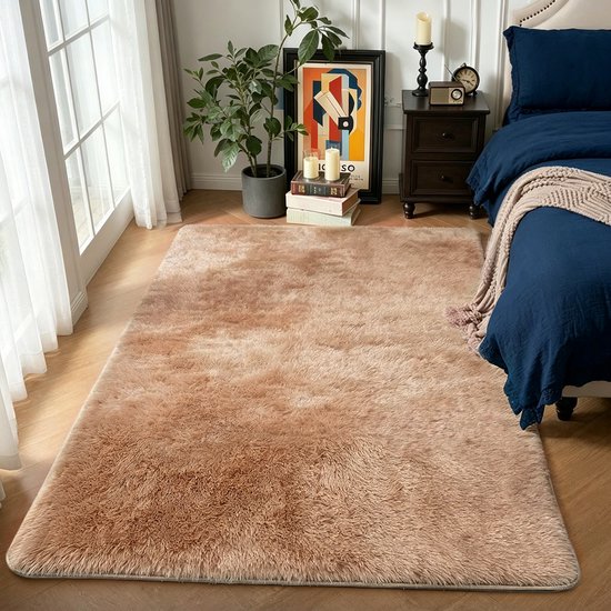 Taupekleurig shaggy vloerkleed in een slaapkamer naast een bed met een blauw dekbed.