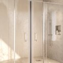 Gesloten douchedeur van glas met twee zilverkleurige handgrepen, met waterdruppels op het glas.