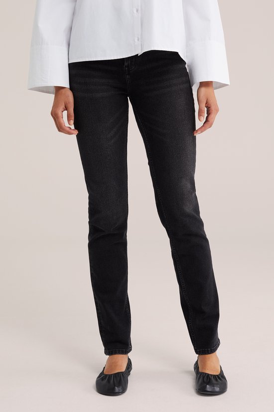 Voorzijde van een zwarte slim fit jeans, gedragen door een model met een witte blouse.