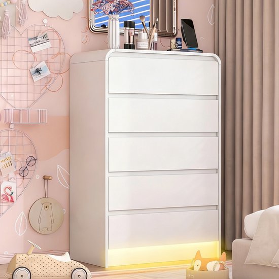 Witte commode met 5 laden en afgeronde hoeken. Met gele LED verlichting aan de onderkant, in een roze slaapkamer.