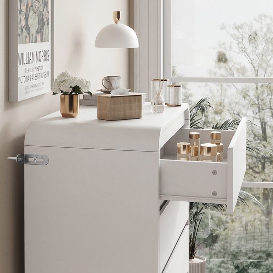 Witte commode met een opengesperde lade met gouden cosmetica.