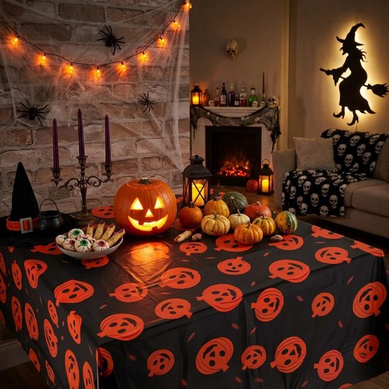 Tafel gedekt met oranje pompoen-tafelkleed in een Halloween-kamer met pompoenen, kandelaars en decoraties.