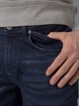 Donkerblauwe jeans met een lichte wassing. Een hand steekt in de zak. Gemaakt van stretchdenim.