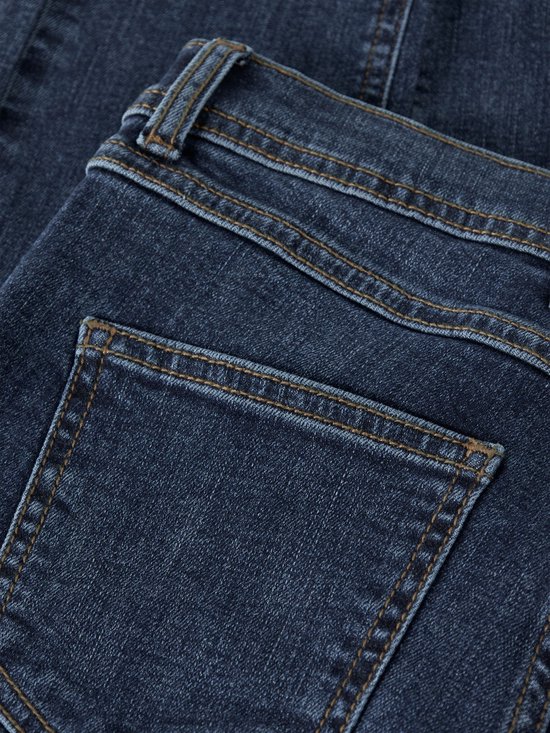 Dichtbij detail van donkerblauwe spijkerbroek met oranje stiksels op de achterzakken en tailleband.