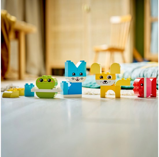 Vijf DUPLO-dieren op een houten vloer, waaronder een rode vis, blauwe kat, gele muis en groene vogel.