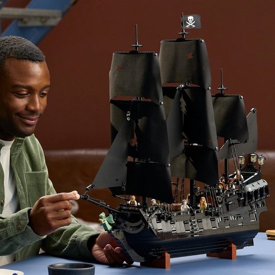 Homme avec le navire pirate LEGO du Capitaine Jack Sparrow avec des voiles noires.