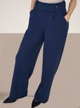 Model draagt donkerblauwe wijde broek met beige top.