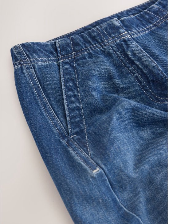 Sluiting en zak van blauwe denim broek met elastische tailleband.