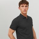 Man met donkere polo met korte mouwen en een kraag, staand