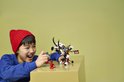 Jongen met rode muts speelt met LEGO NINJAGO speelgoed: een draakachtig beest met ruiter, een rode draak en een ninja met zwaard.