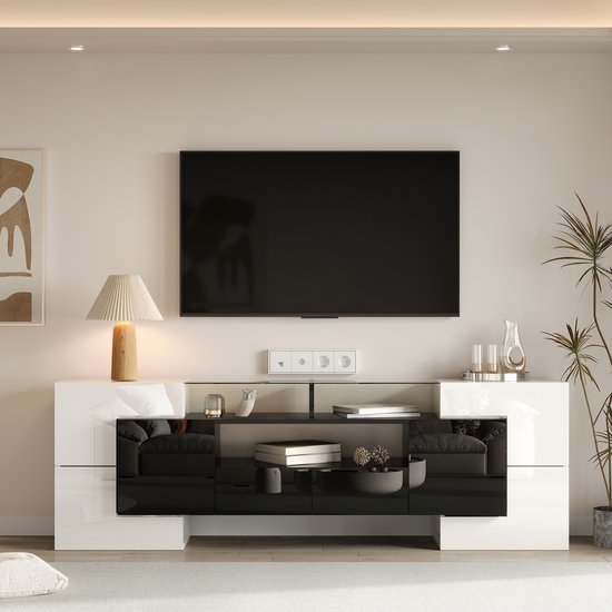 Hoogglans wit en zwart tv-meubel met glazen blad en verlichting. Een lamp staat op het linker deel.