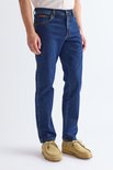 Blauwe Wrangler jeans, gedragen door een man met een beige trui en beige schoenen. Zijaanzicht.