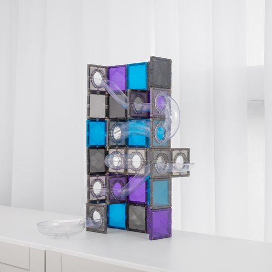Een hoge Connetix knikkerbaan met veel bochten, paarse, blauwe en grijze magneettegels, staand op een witte tafel.