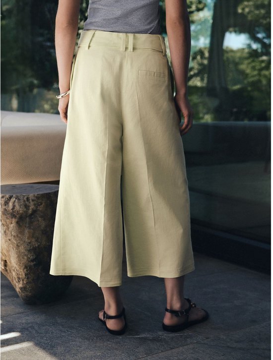 Achterkant van het model in lichtgroene culotte met een grijze top.