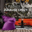 Paarse zitzak in een stijlvolle woonkamer met een print van planten en dieren op de muur.