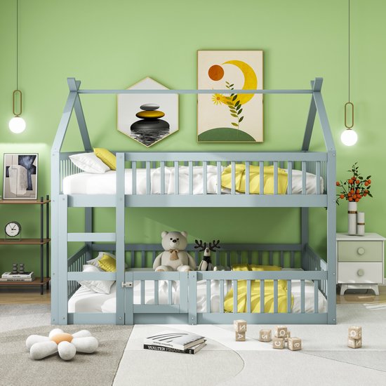 Grijs houten stapelbed met huisvormig dak, gele dekens, witte lakens en knuffels.