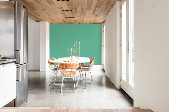 Eethoek met een ronde tafel, stoelen en een groene muur.