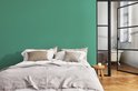 Slaapkamer met een groen geverfde muur achter een bed.