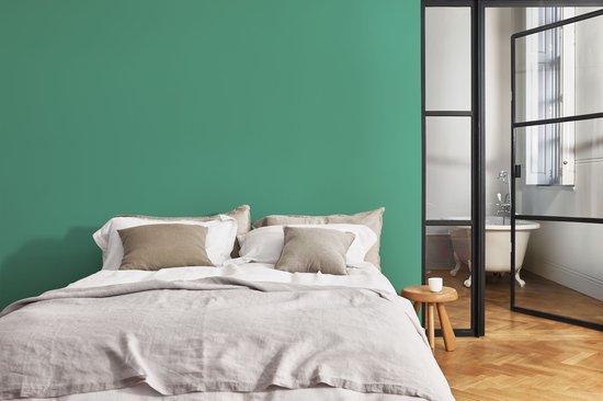 Slaapkamer met een groen geverfde muur achter een bed.