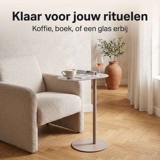Lichtbruin metalen bijzettafeltje naast een fauteuil met mok koffie, boek en glas wijn.