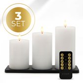 Set van drie witte LED stompkaarsen met vlam en een zwarte afstandsbediening op een standaard.