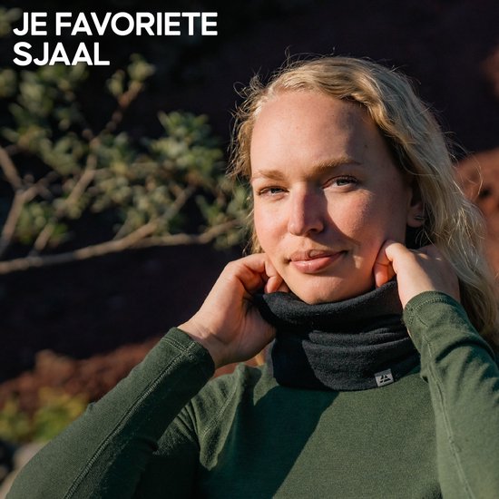 Een vrouw met blond haar die een donkergrijze colsjaal van merinowol in de handen heeft en deze aanpast.
