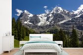 Behang - Fotobehang Bossen voor de bergen de Eiger en Monch in Zwitserland - Breedte 525 cm x hoogte 350 cm