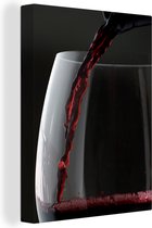 Canvas Schilderij Prachtige close up van een glas rode wijn dat wordt ingeschonken - 60x80 cm - Wanddecoratie