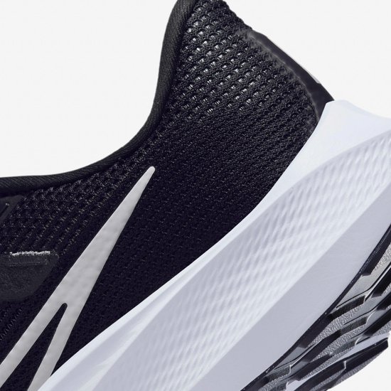 Detail van zwarte Nike hardloopschoen met witte swoosh en witte zoolrand.