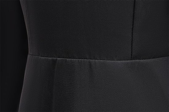 Gros plan sur le tissu noir à fines côtes d'une robe, au niveau de la ceinture.