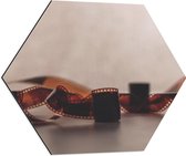 Dibond Hexagon - Uitgerold Filmrolletje tegen Stenen Muur - 60x52.2 cm Foto op Hexagon (Met Ophangsysteem)