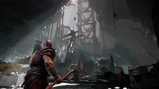 Kratos staat op een rotsachtige ondergrond in een grote grot met constructies.