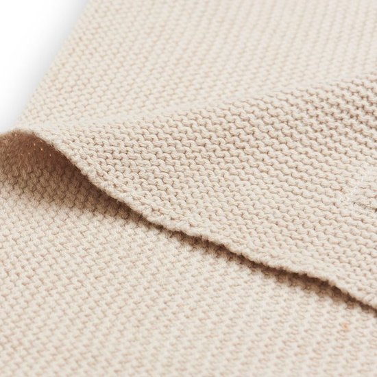 Close-up van de beige gebreide stof van een wiegdeken.