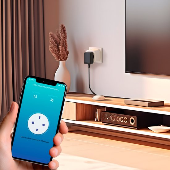 Een slimme stekker aangesloten op een stopcontact bij een tv-meubel. Een hand houdt een telefoon vast met de Calex app.